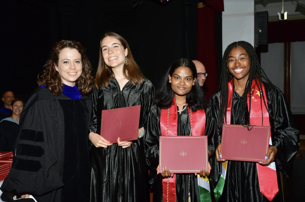Four students holding diplomas on graduation day