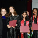 Four students holding diplomas on graduation day