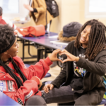 Two students creating a heart shape with hands
